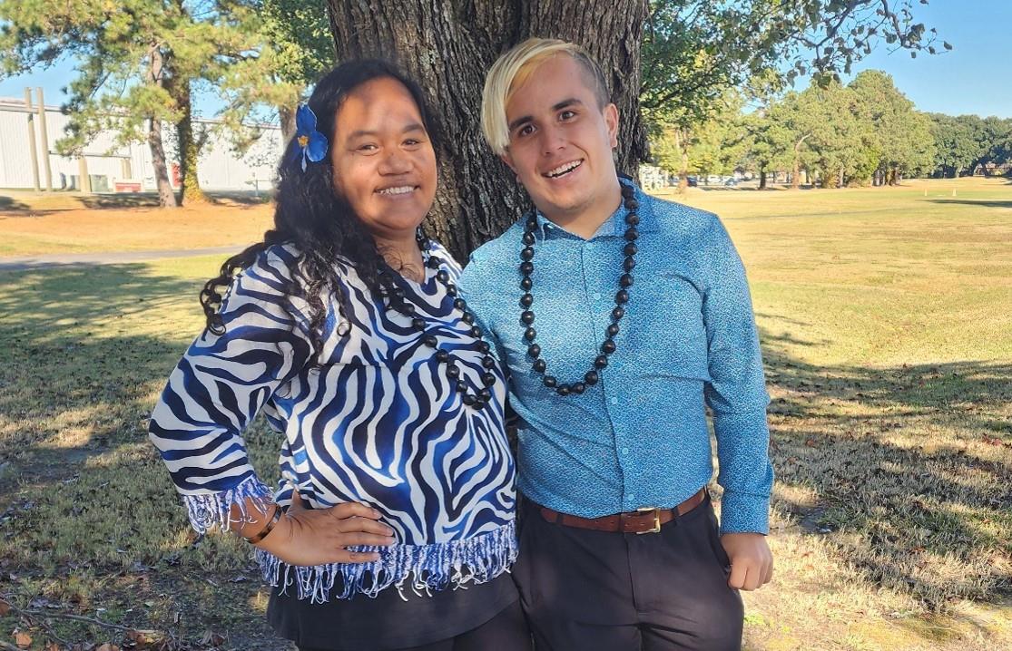 two people standing in front of a tree smiling